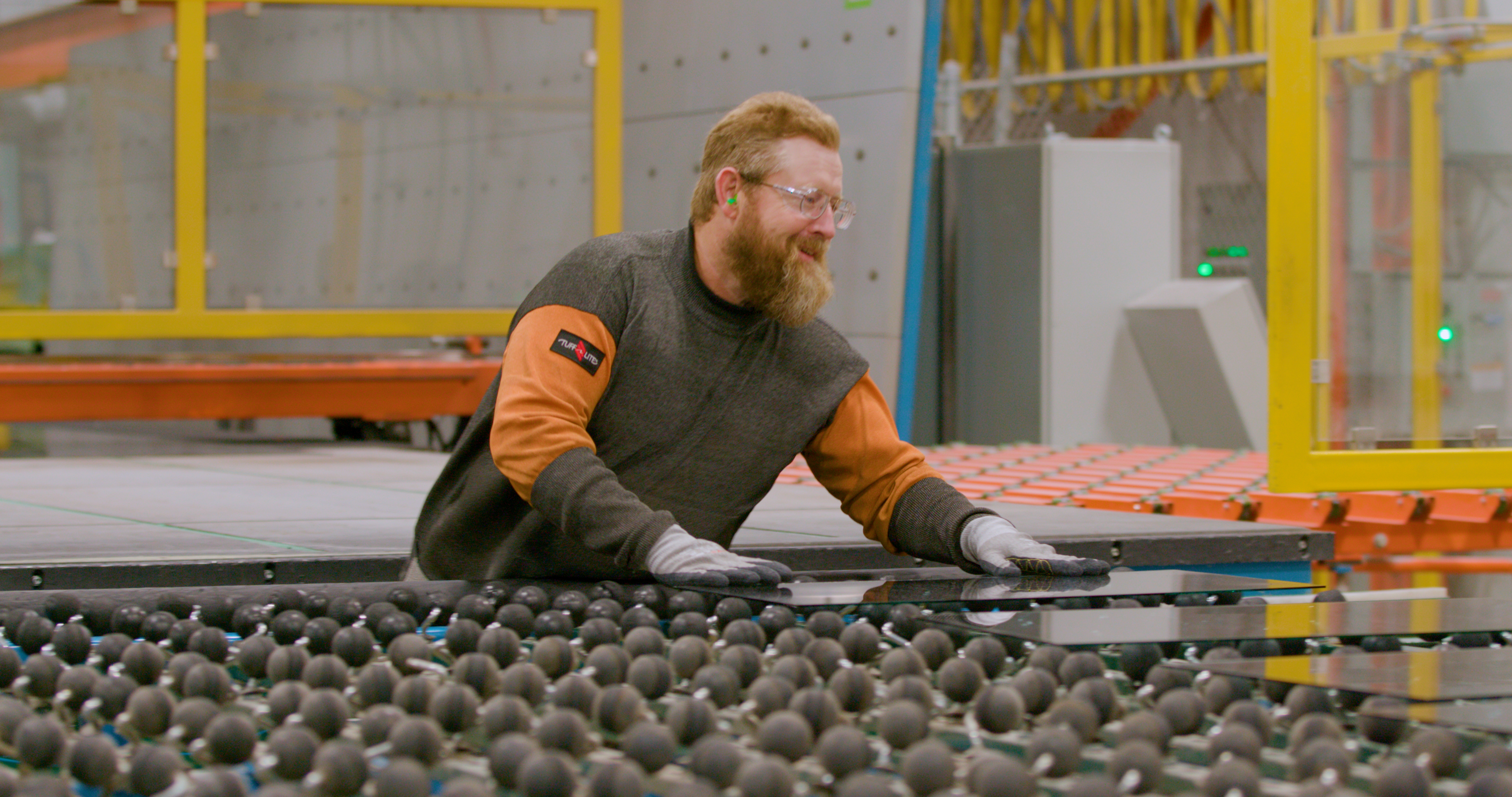 cardinal employee working with glass on glass rollers